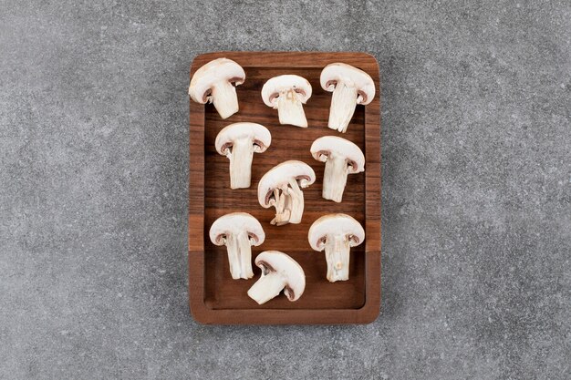 Sliced mushroom on wooden board over grey surface