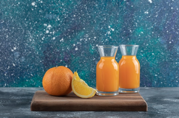 Sliced orange and juice on wooden board. 