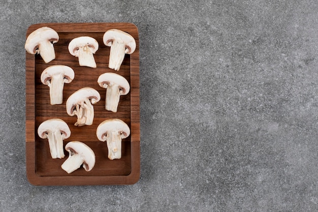 Sliced organic mushroom son wooden board over grey surface