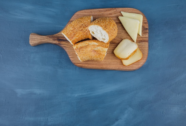 Sliced pastry with cheese and sliced yellow cheese on wooden board. 