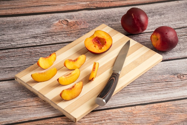 Sliced peach on a wooden cutting board with a cup of ice drink