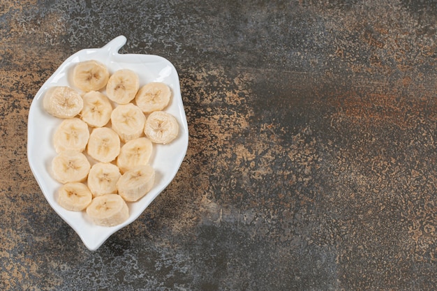 Free photo sliced peeled bananas on white plate.