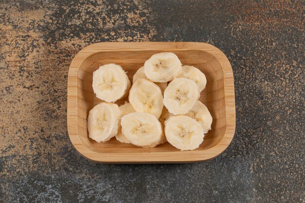 Sliced peeled bananas on wooden plate. 