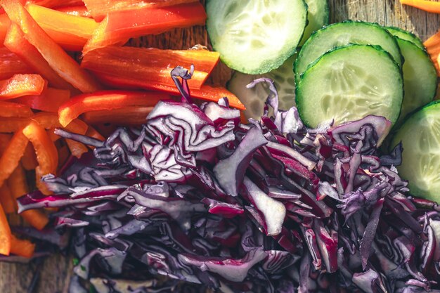 Sliced peppers cucumber and blue cabbage on a cutting board closeup