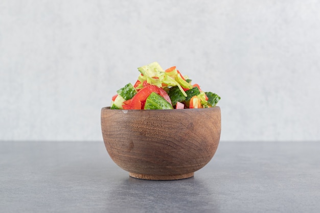 Sliced peppers, cucumbers and pomegranate seeds in wooden bowl. High quality photo