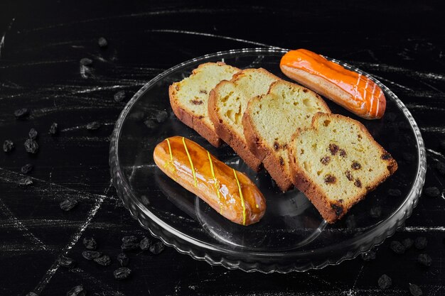 Sliced pie in a glass platter with eclairs.