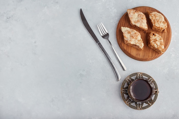 Sliced pie on a wooden platter with a glass of tea, top view. 