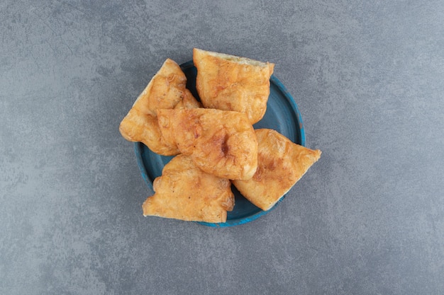 Sliced piroshki with potatoes on blue plate. 