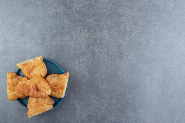 Sliced piroshki with potatoes on blue plate.