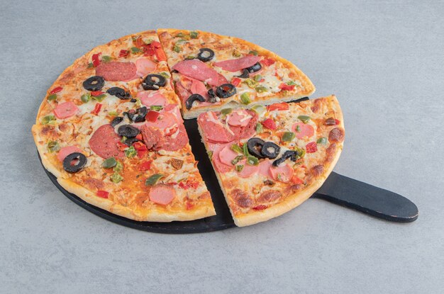 Sliced pizza on a black board on marble 