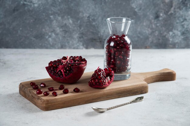 Sliced pomegranate with jug on wooden board. 