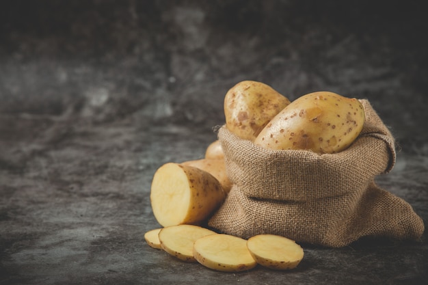 Free photo sliced ​​potatoes put around potato sack on gray floor