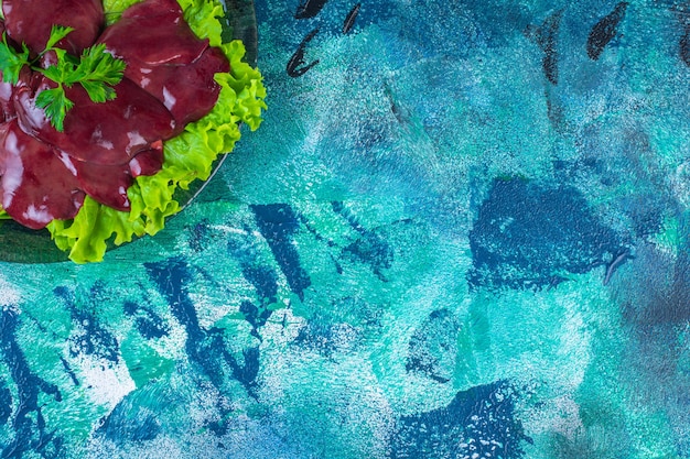 Free photo sliced radish and offal on a lettuce leaf on the plate, on the blue background