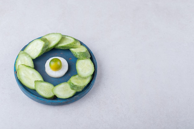 Free Photo sliced radish with kumquat next to sliced cucumber on wooden plate, on the marble.