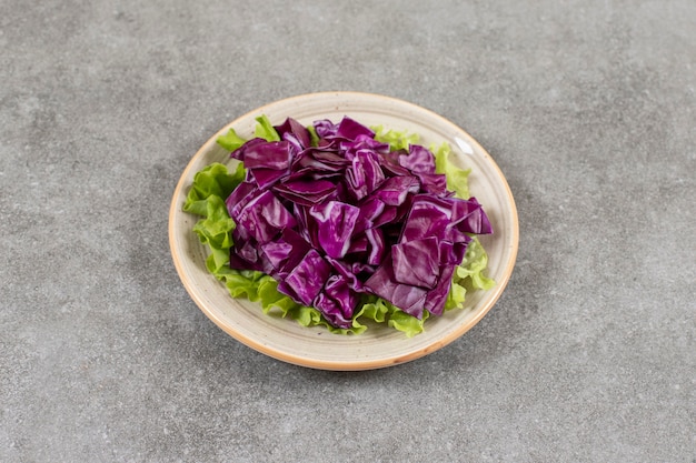 Sliced red cabbage on a plate, on the marble table. 