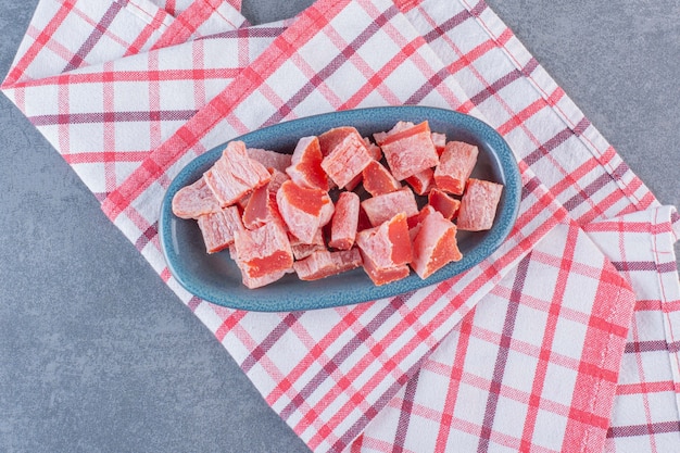 Sliced red marmalade in a plate on tea towel , on the marble surface