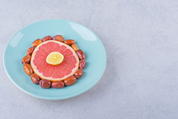 Sliced ripe grapefruit, lemon and silverberries on blue plate.