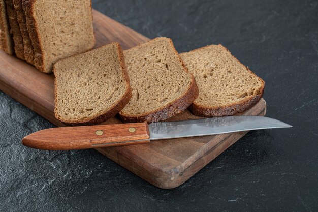 Sliced rye bread placed on wooden cutting board