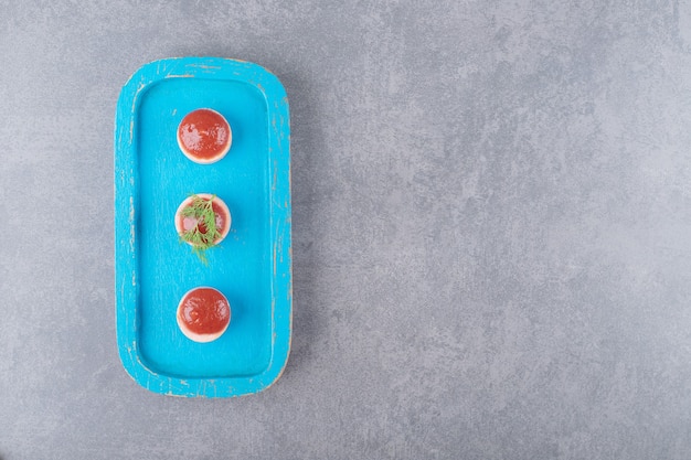 Free photo sliced sausages with ketchup on blue wooden board