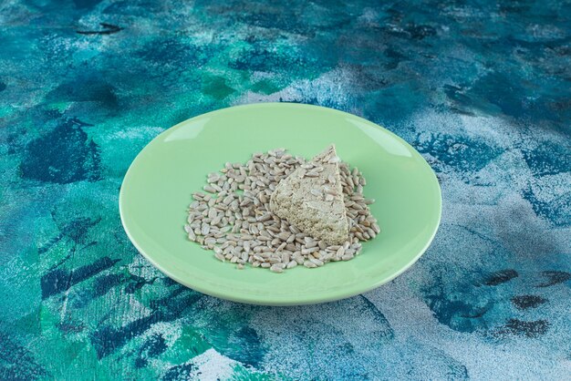 Sliced sunflower halva with seeds on the plate, on the marble table.