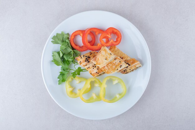 Sliced sweet pepper, parsley and pancakes with meat on plate, on the marble.