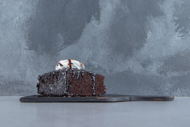 Sliced of tasty chocolate brownie with cream on cutting board. High quality photo