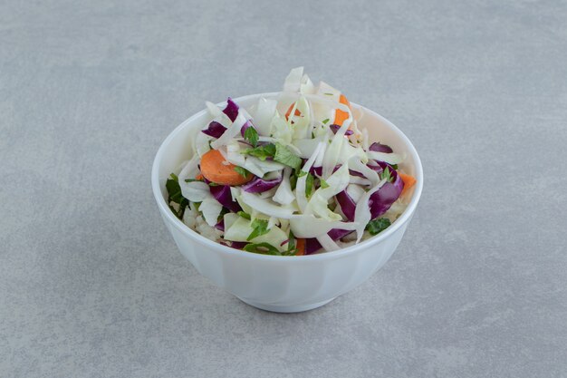 Sliced tomato, greens, red cabbage in bowl , on the marble background.