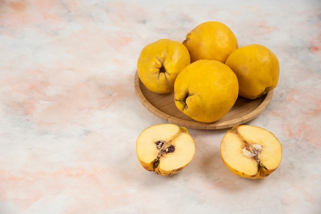 Free photo sliced and whole fresh quince fruits on wooden plate.