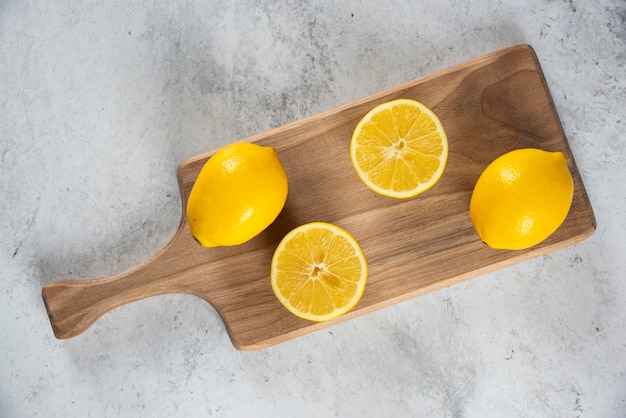 Free photo sliced and whole lemons with wooden reamer .