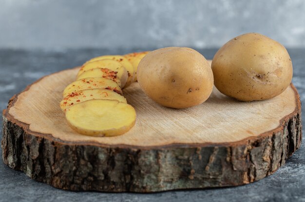 Sliced and whole potatoes on wooden board