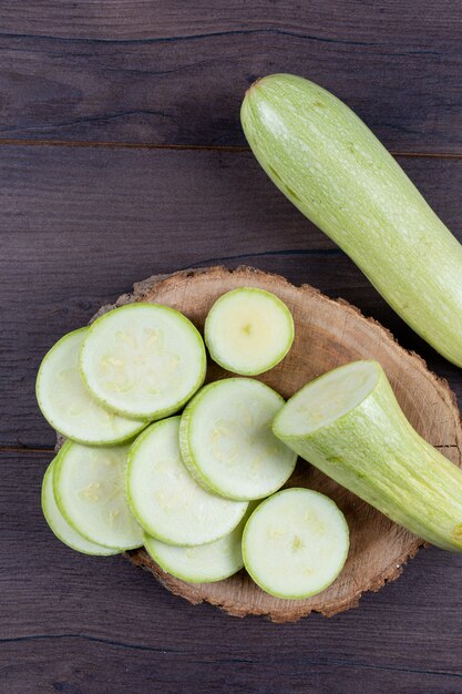 sliced zucchinis on stub and dark wooden table.