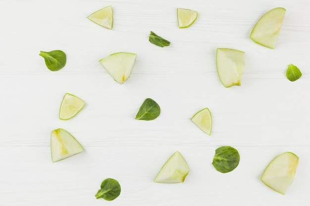 Slices of apples lime and green leaves on a white background