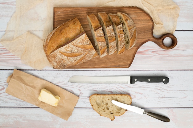 Free Photo slices of bread; knife; butter on paper and butterknife on wooden table