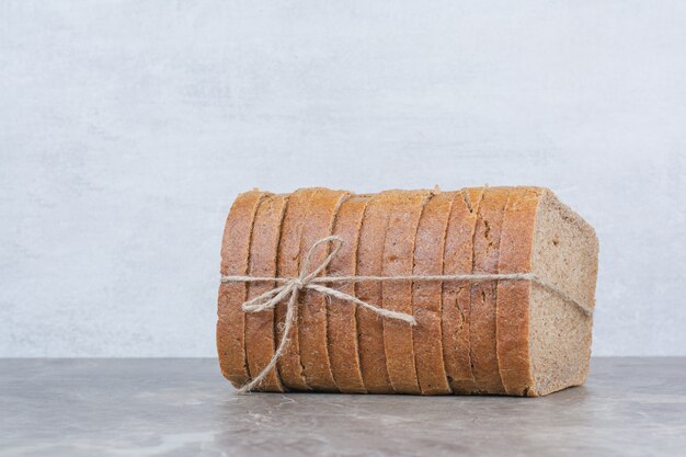 Slices of brown bread in rope on marble surface