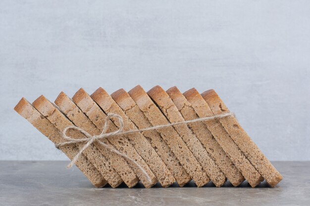 Slices of brown bread in rope on marble surface