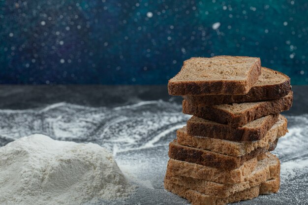 Slices of brown bread with flour on a colorful background. 