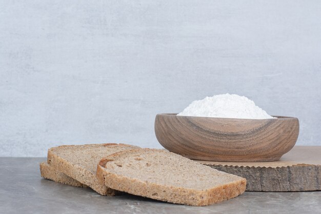 Slices of brown bread with flour on marble surface