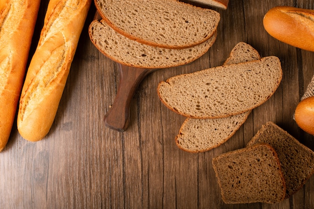 Free Photo slices of brown and white bread on kitchen board with baguette