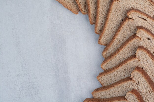 Slices of fresh brown breads on marble background.