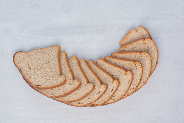 Slices of fresh brown breads on marble background.