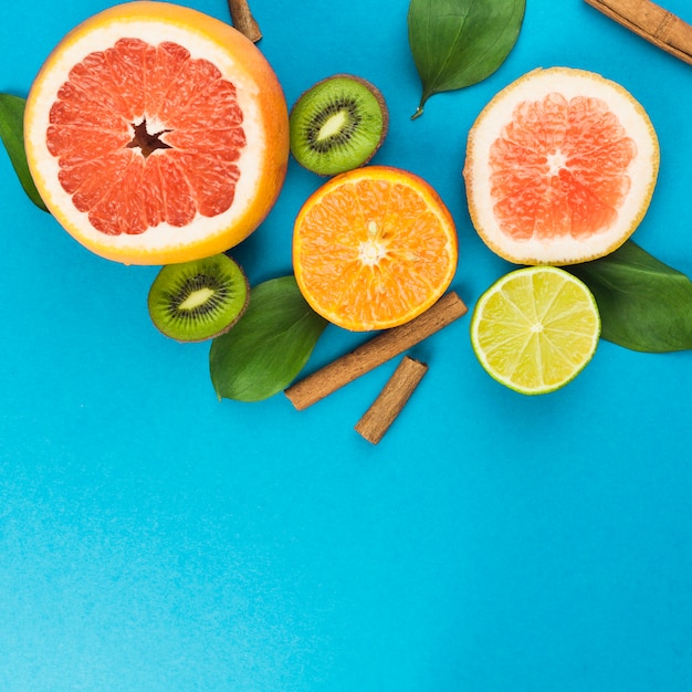 Free photo slices of fresh fruits near cinnamon and foliage