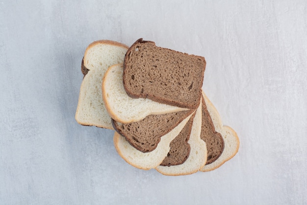 Slices of fresh white and brown breads on marble background.