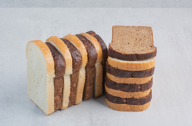 Slices of fresh white and brown breads on marble background.