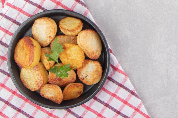 Slices of fried potatoes on black plate.