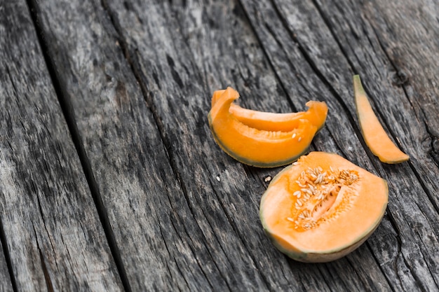 Free photo slices and halved of musk melon on an old wooden table