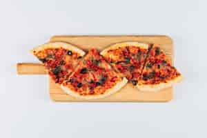 Free photo slices of a pizza in a pizza board on a bright white stucco background. flat lay.