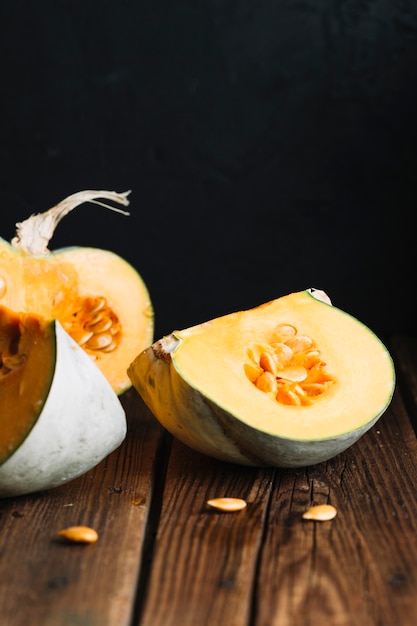 Slices of pumpkin with seeds on wooden background