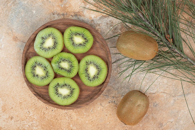 Slices of ripe kiwi on wooden plate. 