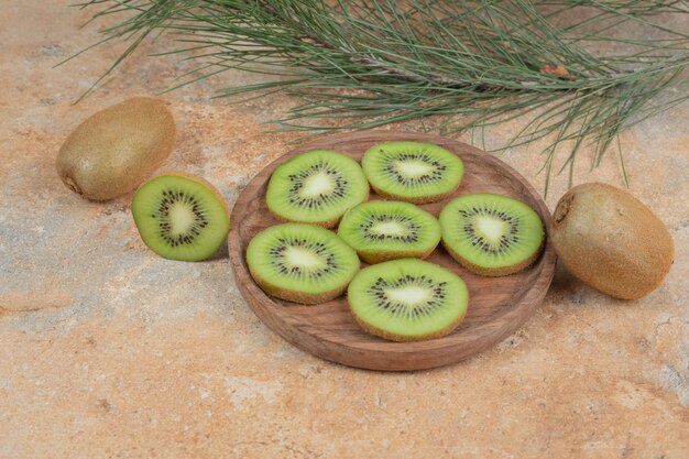 Slices of ripe kiwi on wooden plate. 