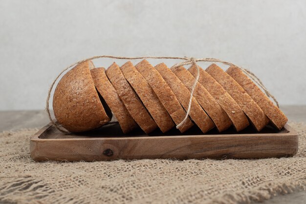 Slices of rye bread on wooden plate with burlap. High quality photo